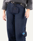 woman holding dark blue denim dog leash with poop bag holder clipped to the leash and woman wearing matching dog treat pouch