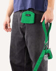 Green corduroy dog treat pouch worn by dog owner holding a matching dog leash