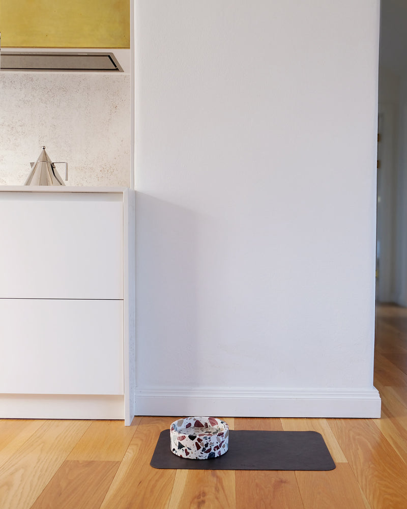 Black PU leather dog bowl mat Le Noof on kitchen floor
