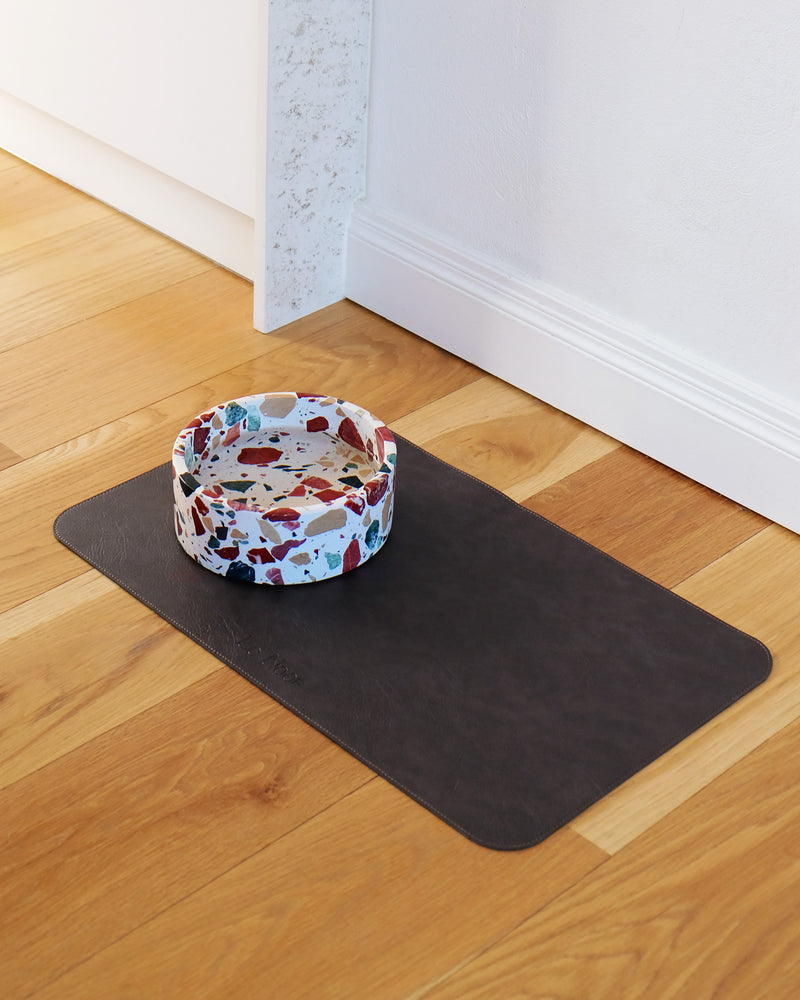 Black Pu leather dog bowl mat on kitchen floor with marble bowl