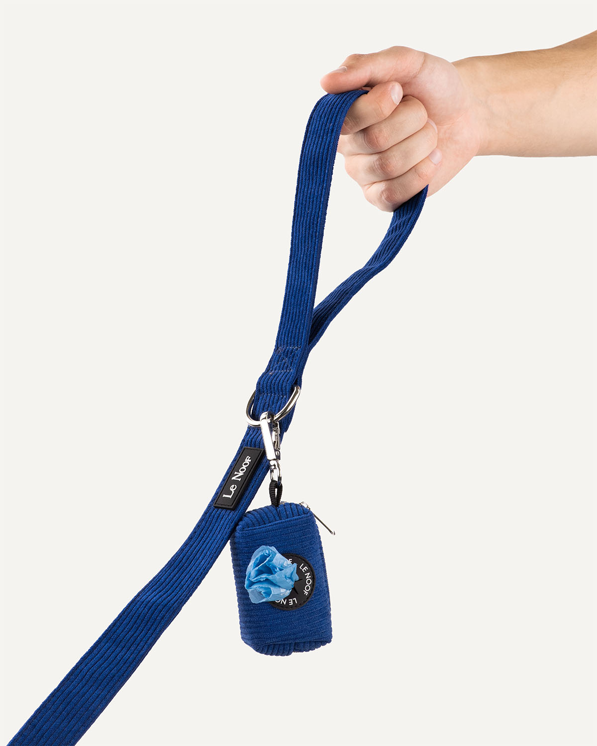Blue corduroy dog leash with poop bag holder held in hand