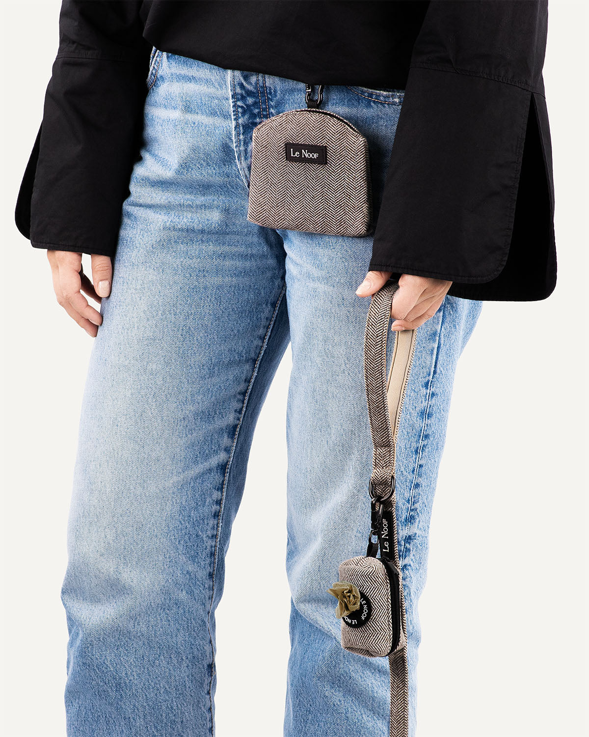 Person holding Brown Herringbone dog leash with matching poop bag holder clipped to it