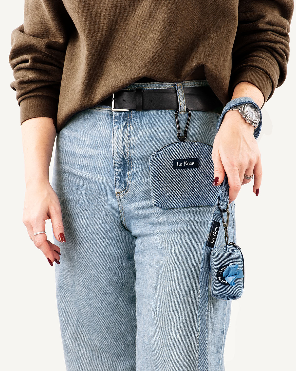 Light blue denim dog treat pouch on woman who is holding a matching leash with poop bag holder attached to it