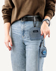 Light blue denim dog treat pouch on woman who is holding a matching leash with poop bag holder attached to it