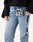Person holding modern geometric print dog leash with matching poop bag holder attached to it and dog treat pouch clipped to jeans